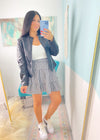 Woman taking a mirror selfie wearing a checkered skirt, white top, and sneakers in a room with colorful decor.