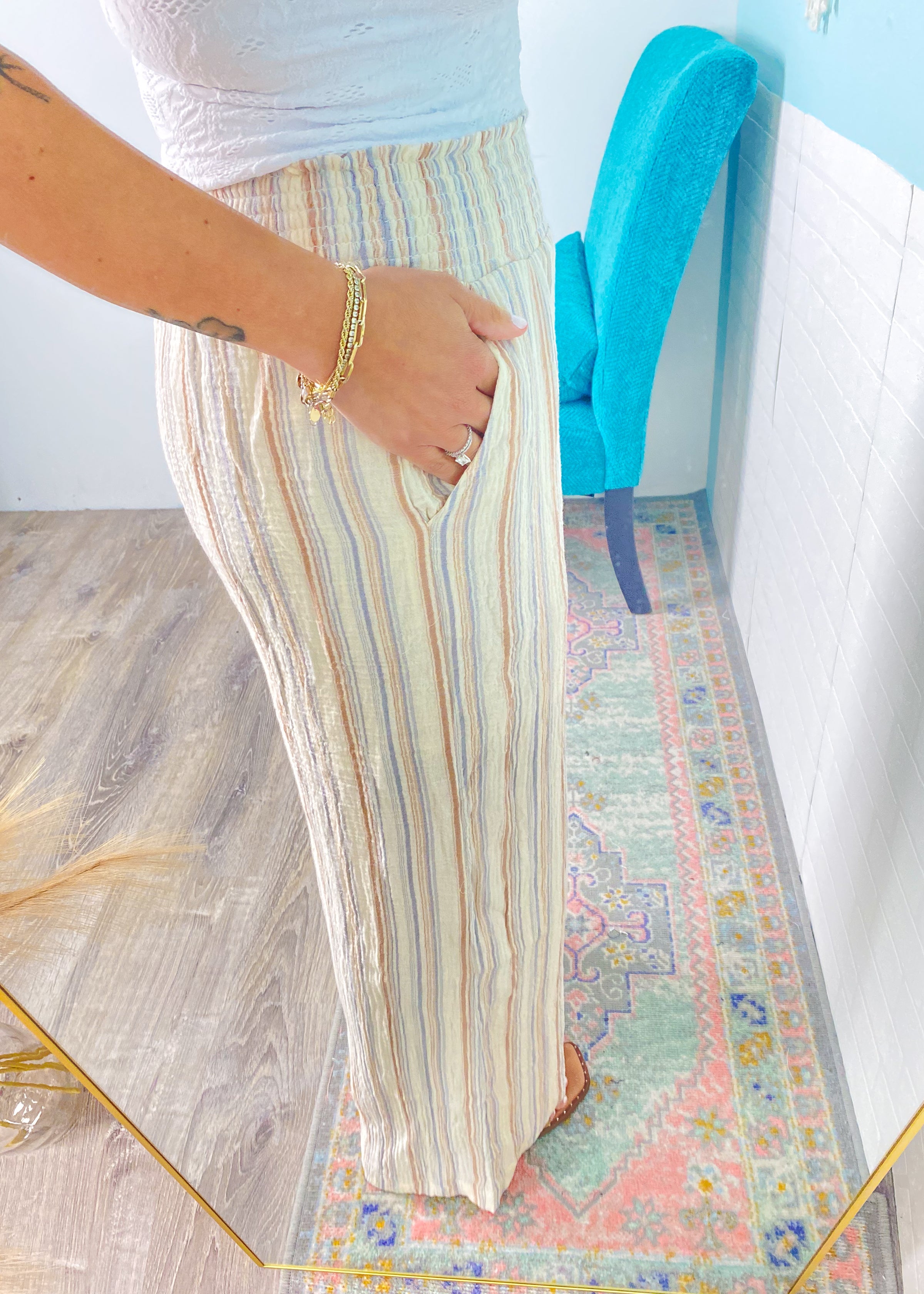 Person wearing a colorful striped skirt on a patterned rug with a blue object in the background.