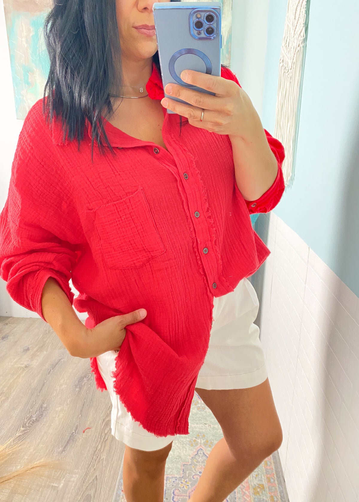 Person wearing a red textured shirt taking a mirror selfie.