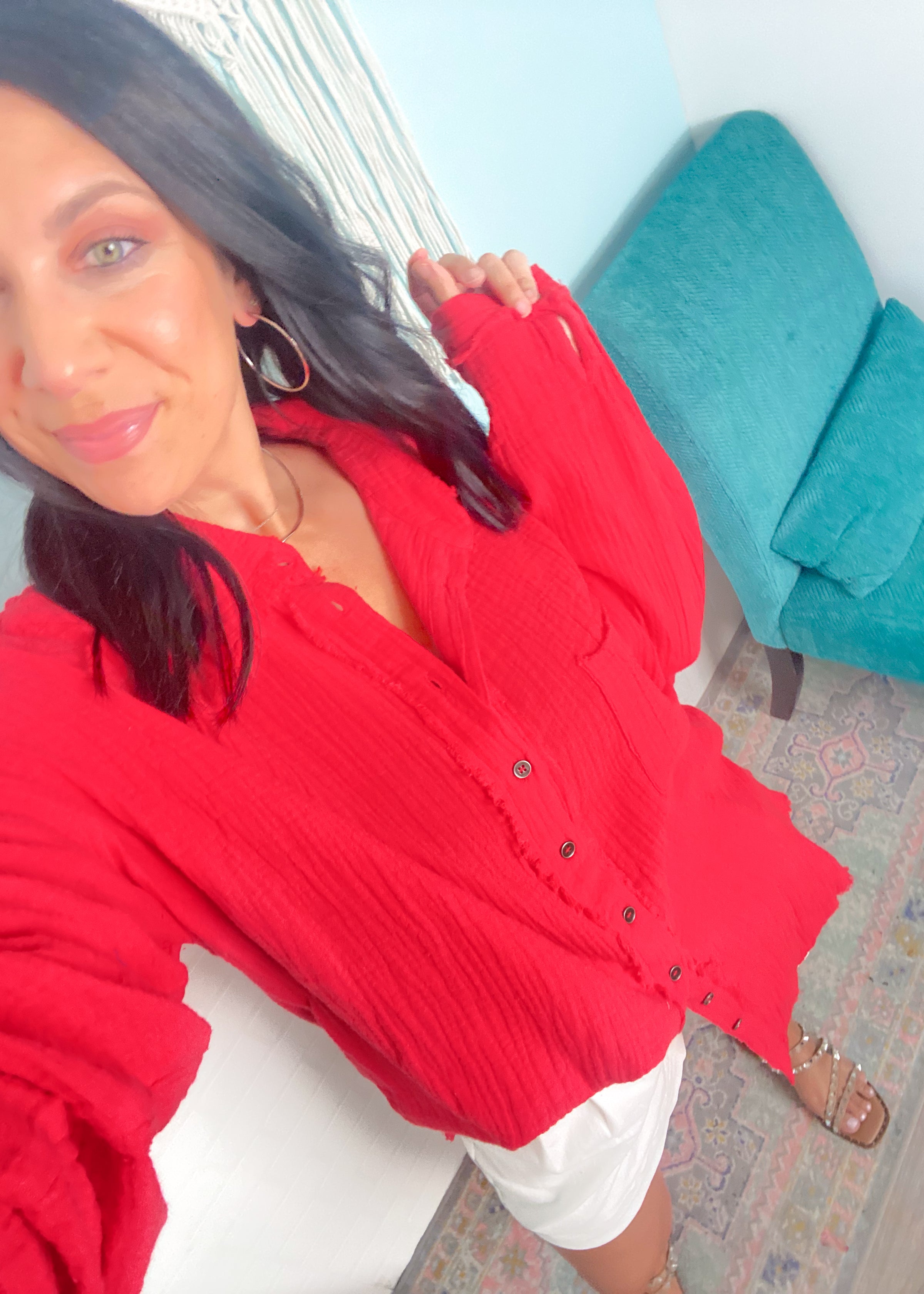 Woman wearing a red blouse sitting on a couch with a blue pillow.